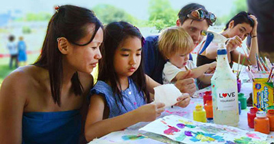Young girl making art with her family at a Love Yourself Project event